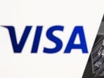 Credit card is seen in front of displayed Visa logo