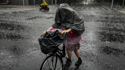 A woman wears a trash bag over her head to protect herself from heavy rain. (REUTERS)