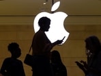 People walk past the Apple logo