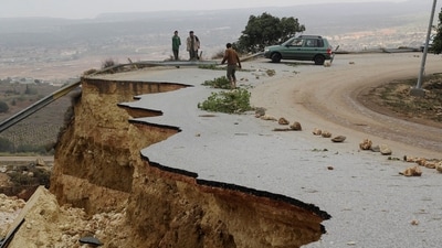 People stand on a damaged road as a powerful storm and heavy rainfall hit Shahhat City, Libya, on September 11. (Omar Jarhman / Reuters) People stand on a damaged road as a powerful storm and heavy rainfall hit Shahhat City, Libya, on September 11. (Omar Jarhman / Reuters)