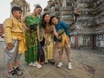 Chinese family tourists rent traditional Thai costumes and take selfies at Wat Arun, or the "Temple of Dawn," in Bangkok, Thailand.