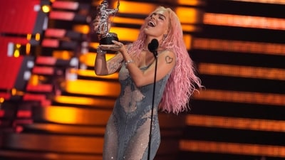 Karol G accepts the award for best collaboration for TQG during the MTV Video Music Awards. She looked stunning in a silver see-through gown, bubblegum pink curly locks, striking glam, and striking jewels. (Charles Sykes/Invision/AP) Karol G accepts the award for best collaboration for TQG during the MTV Video Music Awards. She looked stunning in a silver see-through gown, bubblegum pink curly locks, striking glam, and striking jewels. (Charles Sykes/Invision/AP)