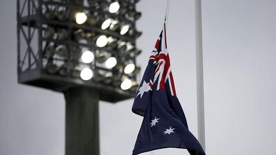 The Australian flag flies at half mast under lights at the Sydney Cricket Ground.