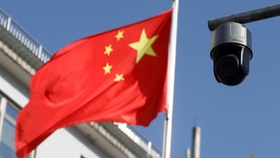 A security surveillance camera overlooking a street is pictured next to a nearby fluttering flag of China in Beijing. (Reuters)