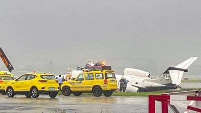 Officials gather around a damaged aircraft after it veered off the runway with six passengers and two crew members on board at the Mumbai airport (PTI) Officials gather around a damaged aircraft after it veered off the runway with six passengers and two crew members on board at the Mumbai airport (PTI)