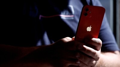 A man poses with an Apple iPhone 12 in a mobile phone store in Nantes, France. (REUTERS)