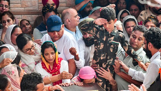 Son of Colonel Manpreet Singh salutes as family members and relatives mourn near his mortal remains before his last rites, at his native place in Mohali. (PTI)