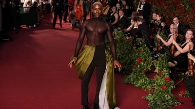 Ncuti Gatwa walked the red carpet in a see-through shirt and black pants featuring olive green and pearl-white train attached to the waist. He completed the ensemble with heeled boots from Christin Louboutin, statement rings, and silver grey hairdo.&nbsp; (REUTERS)