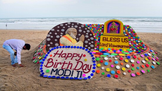 Renowned sand artist Sudarsan Pattnaik creates a sand sculpture of Prime Minister Narendra Modi on his birthday eve and on the occasion of Vishwakarma Puja using Konark wheels in Puri.(PTI)