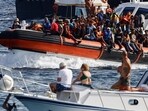 An Italian Coast Guard vessel carrying migrants rescued at sea passes between tourist boats, on the Sicilian island of Lampedusa, Italy, September 18, 2023. REUTERS/Yara Nardi