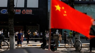 A China's flag flutters near people lining up to get tested at a makeshift nucleic acid testing site. (File image) (REUTERS)
