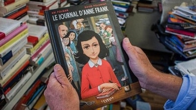 A man holds a copy of the graphic novel version of The Diary of Anne Frank, by Israeli writer-director Ari Folman and illustrator David Polonsky, in Paris on September 18, 2017. (Gent Shkullaku/AFP) A man holds a copy of the graphic novel version of The Diary of Anne Frank, by Israeli writer-director Ari Folman and illustrator David Polonsky, in Paris on September 18, 2017. (Gent Shkullaku/AFP)