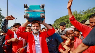 Congress leader Rahul Gandhi, wearing the porters' trademark red shirt and badge, carries luggage over his head during an interaction with porters at Anand Vihar railway station, in New Delhi (PTI) Congress leader Rahul Gandhi, wearing the porters' trademark red shirt and badge, carries luggage over his head during an interaction with porters at Anand Vihar railway station, in New Delhi (PTI)