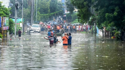 Commuters stand at one side of a road after it was flooded due to heavy rains, in Nagpur, Saturday, Sept. 23. (PTI)