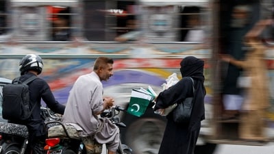A woman speaks with a customer while selling national flags, ahead of Pakistan's Independence Day, along a road in Karachi, Pakistan August 10, 2023. REUTERS/Akhtar Soomro     TPX IMAGES OF THE DAY (REUTERS)