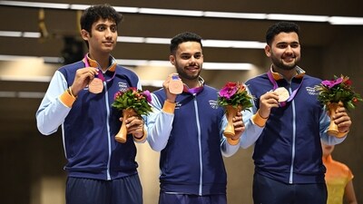Bronze medallist Adarsh Singh, Anish and Vijayveer Sidhu celebrate on the podium after the men's team 25m Rapid Fire Pistol event&nbsp; (REUTERS)