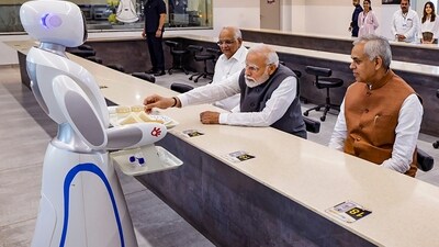 PM Modi, Gujarat Governor Acharya Devvrat and Chief Minister Bhupendra Patel being served tea by robots at Science City ahead of an event marking the completion of 20 years of the ‘Vibrant Gujarat Global Summit’ in Ahmedabad. (PTI)