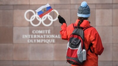 A supporter waves a flag in front of the logo of the International Olympic Committee (IOC) | Image for representation A supporter waves a flag in front of the logo of the International Olympic Committee (IOC) | Image for representation