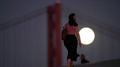 People walk on the roof of the Museum of Art, Architecture and Technology in Lisbon, as a full supermoon rises in the background, Thursday, Sept. 28, 2023. (AP Photo/Armando Franca) (AP)