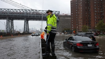A police officer from the NYPD Highway Patrol looks on near cars stuck in a flooded motorway after heavy rains as the remnants of Tropical Storm Ophelia bring flooding across the mid-Atlantic and Northeast, at the FDR Drive in Manhattan near the Williamsburg bridge, in New York City, U.S., September 29, 2023. (REUTERS)
