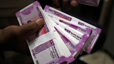 A cashier displays the new 2000 Indian rupee banknotes inside a bank (REUTERS)