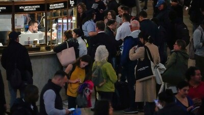 An MTA employee helps commuters as train service has been disrupted due to heavy rains at Grand Central Terminal information booth in New York. (AP)