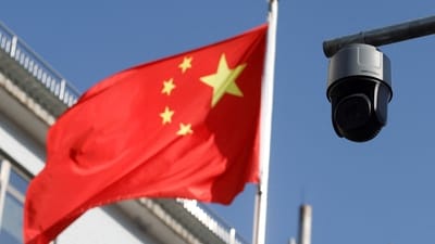 A security surveillance camera overlooking a street is pictured next to a nearby fluttering flag of China in Beijing. (Reuters)