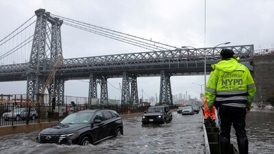A police officer from the NYPD Highway Patrol looks on as motorists drive through a flooded street after heavy rain. (REUTERS)
