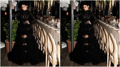 Her outfit includes a modest neckline, long sleeves, a snug bodice, a black waistbelt, and numerous ruffled embellishments on a sheer fabric towards the hem. ( Instagram/@imouniroy)