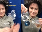 The image shows astronaut Samantha Cristoforetti pouring coffee into a space cup. 
