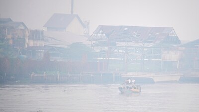 Students ride a wooden boat through the Ogan river, which is covered by smog due to wildfires, in Palembang, South Sumatra province, Indonesia. (Reuters)