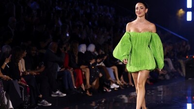 Lola Moreno struts the runway at the L'Oreal Paris show in a neon green balloon dress featuring an off-the-shoulder neckline, full-length billowy sleeves, a mini hem length, and a pleated structure.&nbsp; (REUTERS)