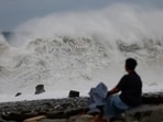 A person sits by the shore while looking at waves breaking as Typhoon Koinu approaches, in Taitung, Taiwan.