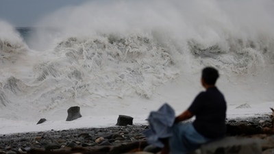 A person sits by the shore while looking at waves breaking as Typhoon Koinu approaches, in Taitung, Taiwan. (REUTERS)