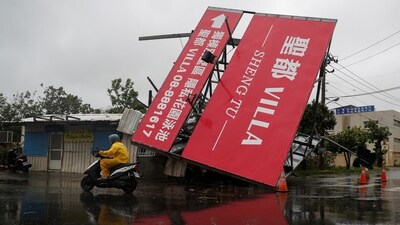 A person on a scooter drives past a fallen billboard after Typhoon Koinu passed the southern tip of Taiwan on October 5. (Reuters)