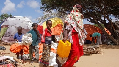 A woman walks with her children, who fled amid drought, to build a makeshift shelter at a camp for the displaced people on the outskirts of Mogadishu, Somalia. (AP) A woman walks with her children, who fled amid drought, to build a makeshift shelter at a camp for the displaced people on the outskirts of Mogadishu, Somalia. (AP)