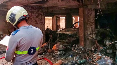 Mumbai: A fire department personnel maintains records as charred vehicles are seen after a fire broke out in a multi-storey residential building in Goregaon area Mumbai. (PTI)