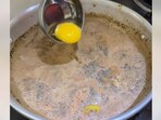The image shows a raw egg being poured in boiling milk tea. The image shows a raw egg being poured in boiling milk tea.