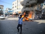 A Palestinian celebrates by a burning Israeli civilian car taken from Kfra Azza kibbutz in Beit Lahiya, Gaza Strip, Saturday, Oct. 7, 2023.