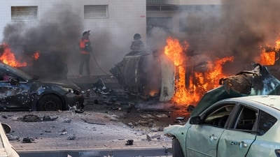 People try to extinguish fire on cars following a rocket attack from the Gaza Strip in Ashkelon, southern Israel, on October 7, 2023. (AFP) People try to extinguish fire on cars following a rocket attack from the Gaza Strip in Ashkelon, southern Israel, on October 7, 2023. (AFP)