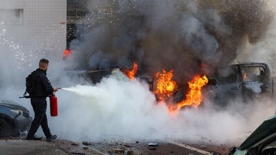 A member of Israeli security forces tries to extinguish fire on cars following a rocket attack from the Gaza Strip in Ashkelon, southern Israel, on October 7, 2023. (AFP) A member of Israeli security forces tries to extinguish fire on cars following a rocket attack from the Gaza Strip in Ashkelon, southern Israel, on October 7, 2023. (AFP)