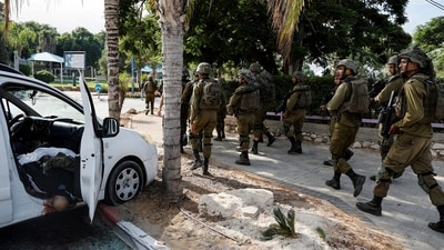 Israeli soldiers walk past the body of a man who was killed following a mass-infiltration by Hamas gunmen from the Gaza Strip. (REUTERS)