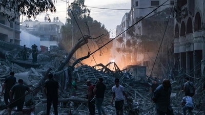 People walk atop the rubble of a tower destroyed in an Israeli air stike in Gaza City (AFP)
