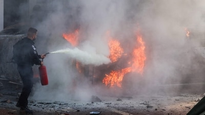Israel-Palestine Latest: A member of Israeli security forces tries to extinguish fire on cars following a rocket attack from the Gaza Strip in Ashkelon, southern Israel. (AFP)