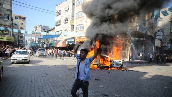 A Palestinian celebrates by a burning Israeli civilian car taken from Kfra Azza kibbutz in Beit Lahiya, Gaza Strip, Saturday, Oct. 7, 2023. A Palestinian celebrates by a burning Israeli civilian car taken from Kfra Azza kibbutz in Beit Lahiya, Gaza Strip, Saturday, Oct. 7, 2023.