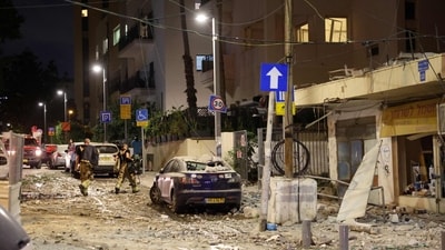 Members of the Israeli security forces walk along a debris-strewn street in Tel Aviv, after it was hit by a rocket fired by Palestinians from the Gaza Strip (AFP)