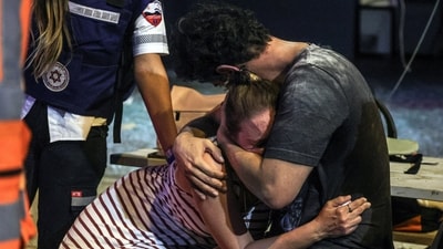 People react at the site where a rocket launched from the Gaza Strip landed in Tel Aviv, Israel, on Saturday. (REUTERS)