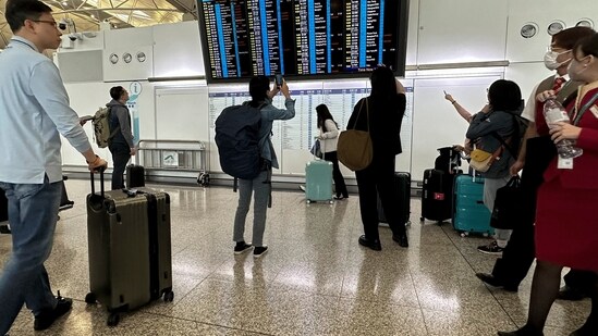 Tropical Storm Koinu: Travelers look at a flights information display which shows some of the flights have been canceled due to the super typhoon Koinu. (AP)