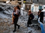 Palestinians carry their belongings as they walk on a debris-strewn street in the aftermath of Israeli strikes, following a Hamas surprise attack, at Beach refugee camp, in Gaza City, October 9, 2023.