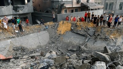 Palestinians gather around the rubble of a building destroyed in Israeli strikes, in the southern Gaza Strip October 9, 2023. (REUTERS)
